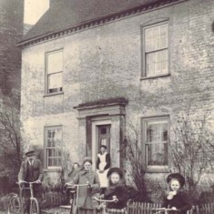 Nurse Kate Micklam with her bicycle, with her family, on the doorstep of Barnards, c 1903. She was the village midwife. 