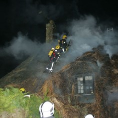 Smoking roof - men at work. They began by creating a break in the thatch in order to prevent the fire spreading to the adjoining properties. (Petersfield Post photo)