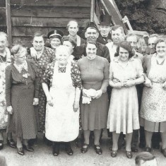 Group of 'waitresses' by wooden wall.