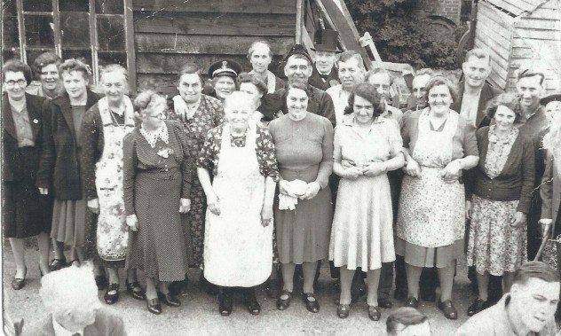 Group of 'waitresses' by wooden wall.