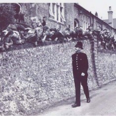 P.C.Dennis Thorne walks along the school wall, lined with children. Taken in 1949 by the New York Sunday News magazine.