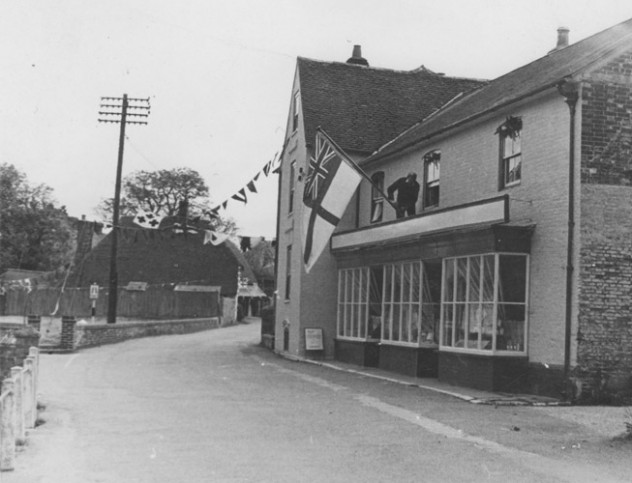 Man erecting Royal Navy Ensign on Country Store.
