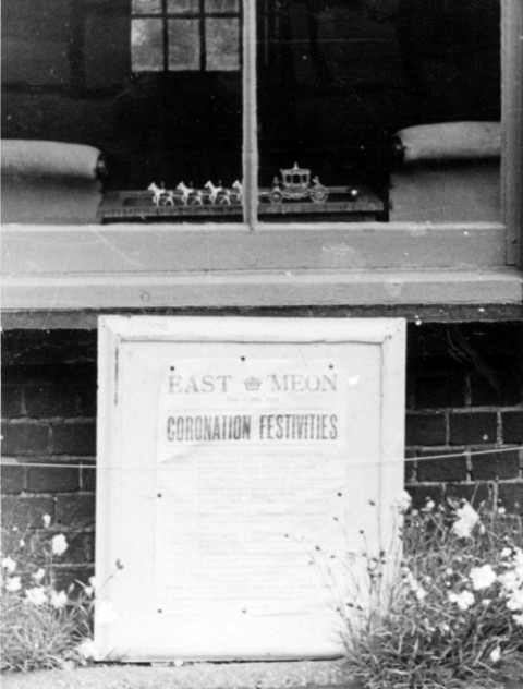 Window during Coronation with poster and miniature state coach and horses.