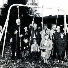 At the Opening of the Under-9s playground in the grounds of the Village Hall, 1996, standing, left to right, Jean Rockett, Joan Haines, Brigadier John Simpson (Chair of VH Committee), Monique Aldridge, Wilson Atkinson (Chair, Parish Council), Freddie Standfield, Peter Street, Rev Peter Wadsworth, (seated) Susan Hull, to her right, Zara Kitcher