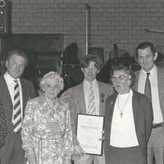 Presentation by Atkinsons to farm hand Ginger Phillips. L to R, Eileen A, Wilson A, Sarah (Wilson's mother), Ginger Phillips with certificate, Kate, Michael and Jane Atkinson 