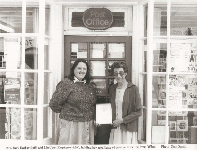 Jean Emptage with certificate and Judy Barber outside door of Post Office