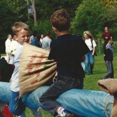 Boys sack-fighting on slippery pole